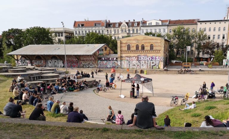 Große Menschenmenge sitzt auf den Stufen des Amphitheaters im Görlitzer Park bei einer Kiezversammlung.