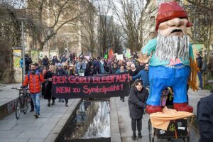 Demonstrationszug mit Banner „Der Görli bleibt auf! Nein zu Symbolpolitik!“ und einer großen Gartenzwerg-Figur, dahinter viele Teilnehmende.