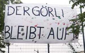 Banner mit bunten Kinderhandabdrücken und der Aufschrift „Der Görli bleibt auf!“, aufgehängt am Zaun des Görlitzer Parks.