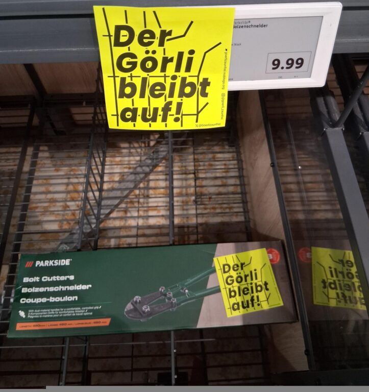 Aufkleber „Der Görli bleibt auf!“ im Baumarktregal direkt neben einem beworbenen Bolzenschneider für 9,99 Euro.