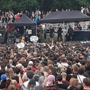 Große Menschenmenge vor einer Bühne bei einer Demo, mit Schildern „Görli bleibt auf!“ und „Noch alle Latten am Zaun?“