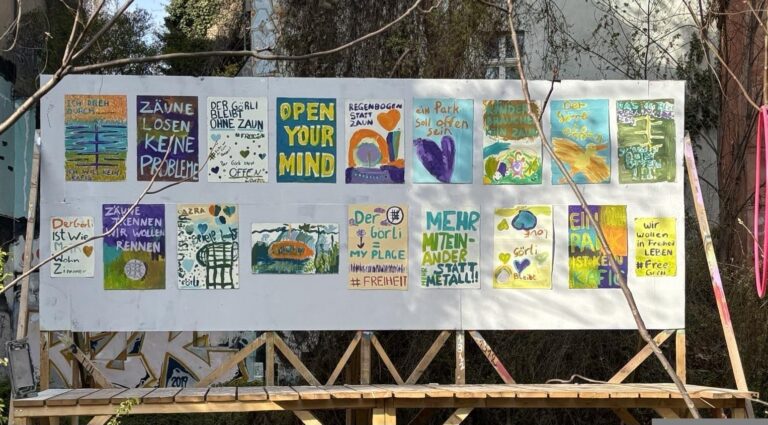Ausstellungstafel mit von Kindern aus dem Kiez gemalten Bildern und Sprüchen wie „Zäune lösen keine Probleme“ und „Open your mind“